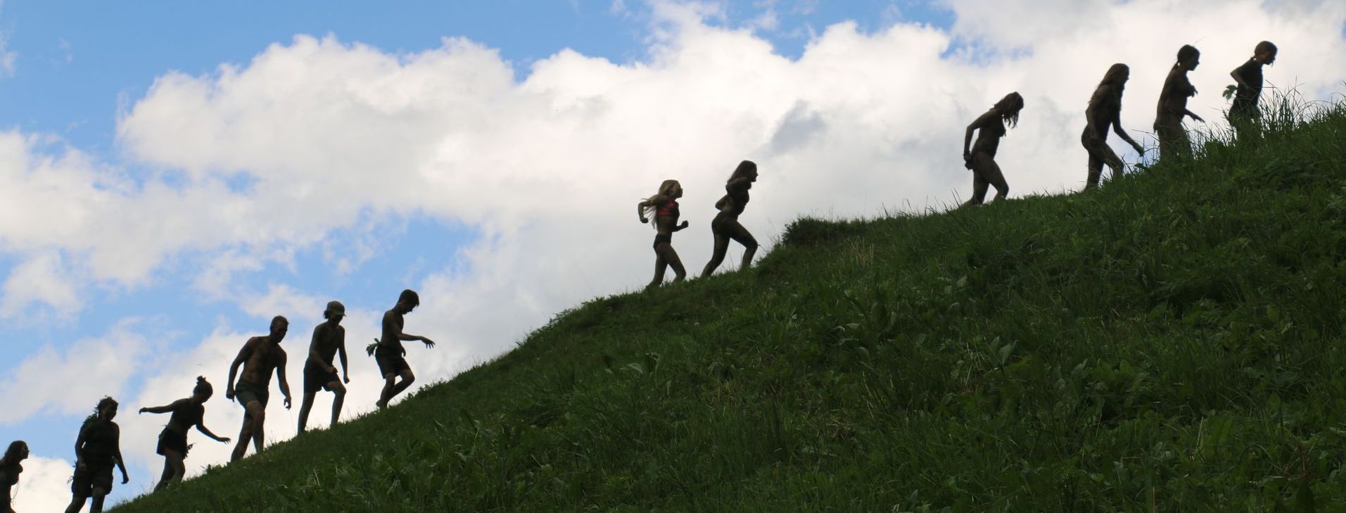 Gruppe von Jugendlichen schleicht einen Grashügel hinauf – Natur Erleben im Zürcher Oberland`