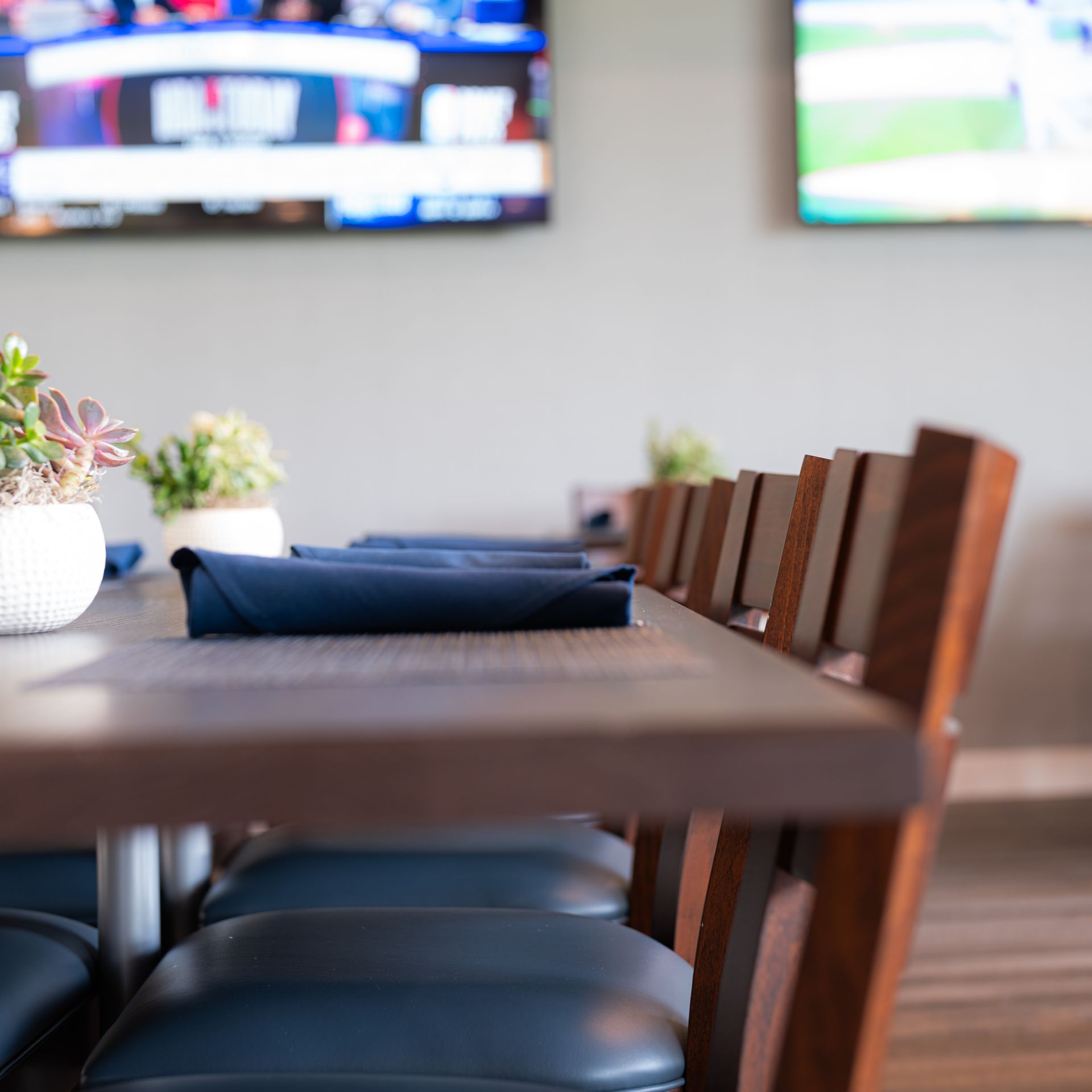 A long table with chairs and a television on the wall.