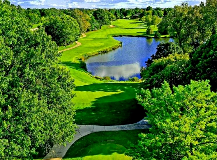 An aerial view of a golf course surrounded by trees and a lake.