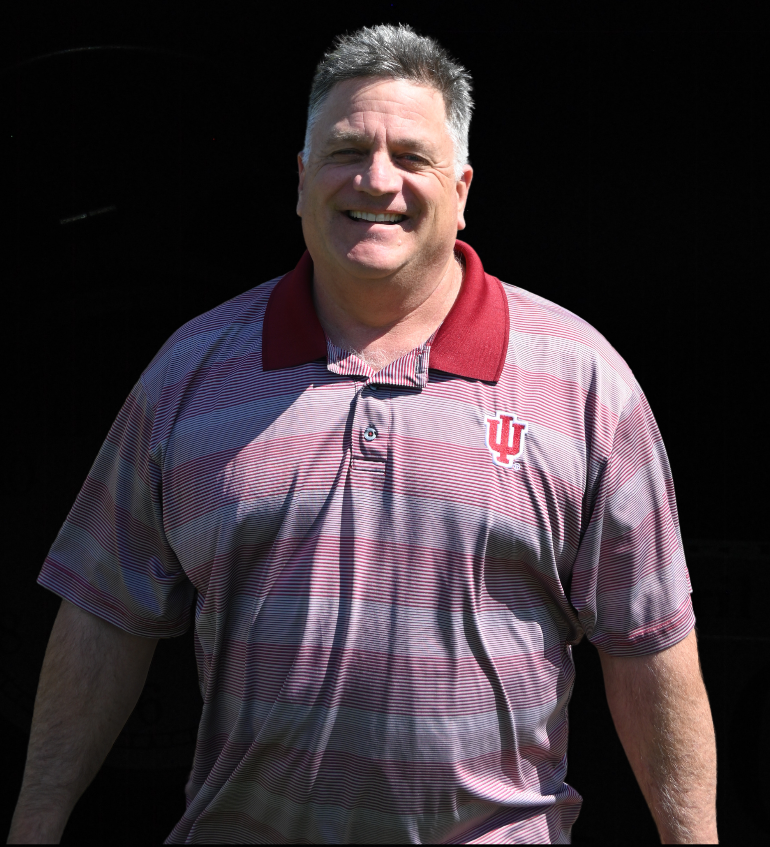 A man in a green striped shirt is smiling for the camera.