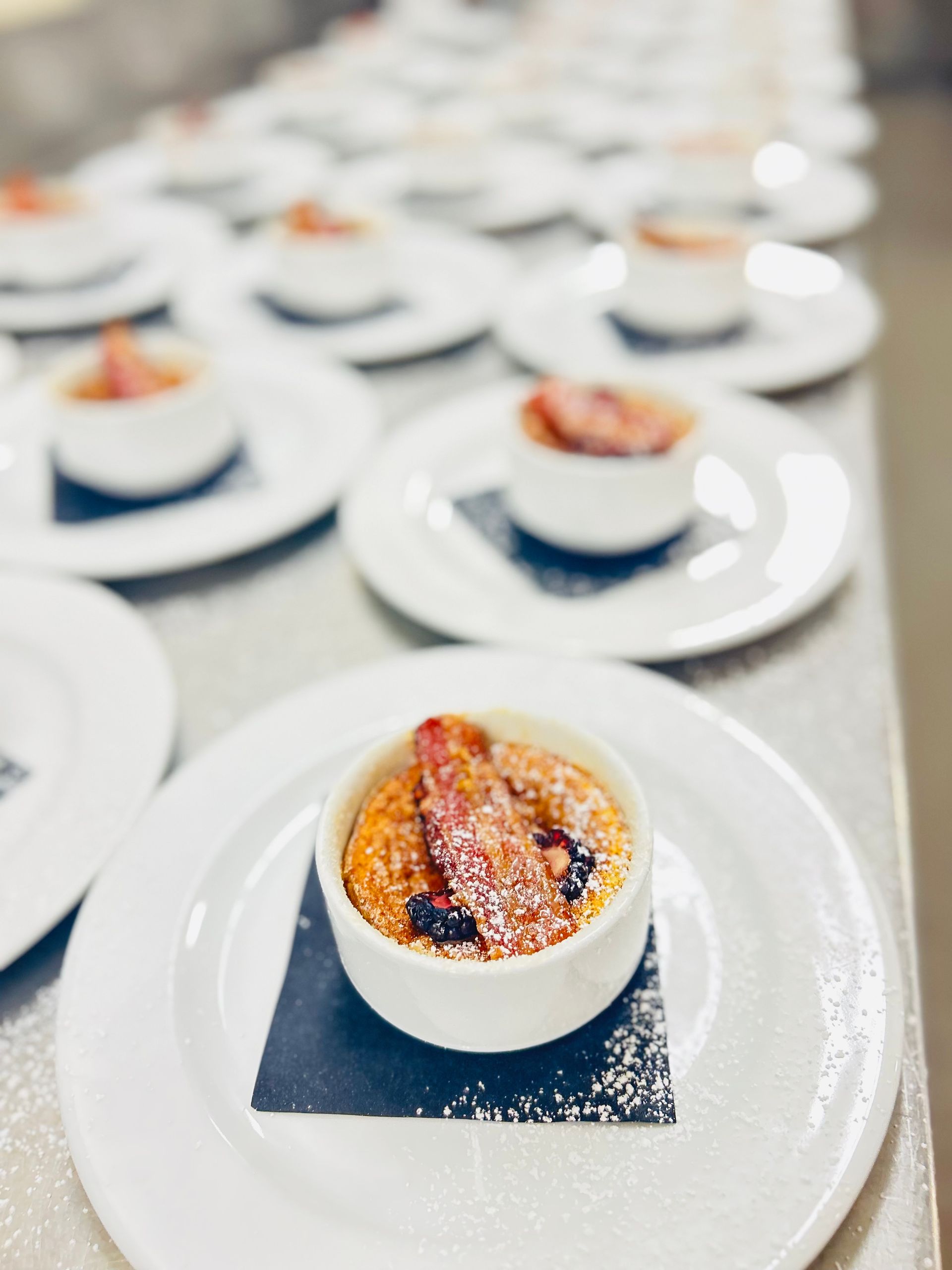 A bowl of food is on a white plate on a table.