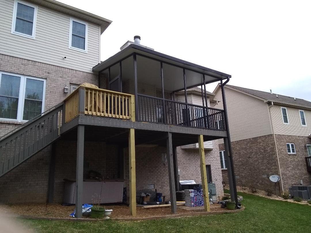 Backyard deck with stairs, wooden railing, and a covered patio beside a brick house