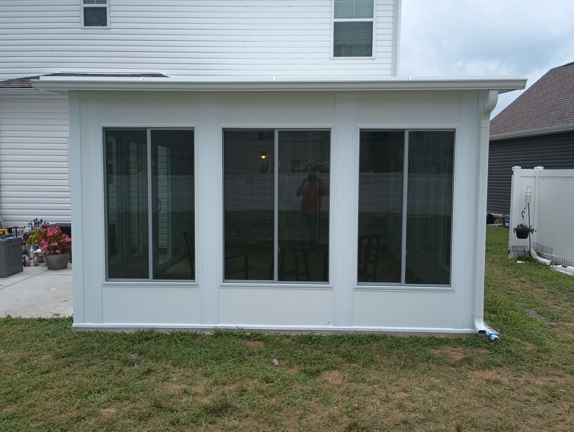 White enclosed patio sunroom with sliding glass doors on the back of a house