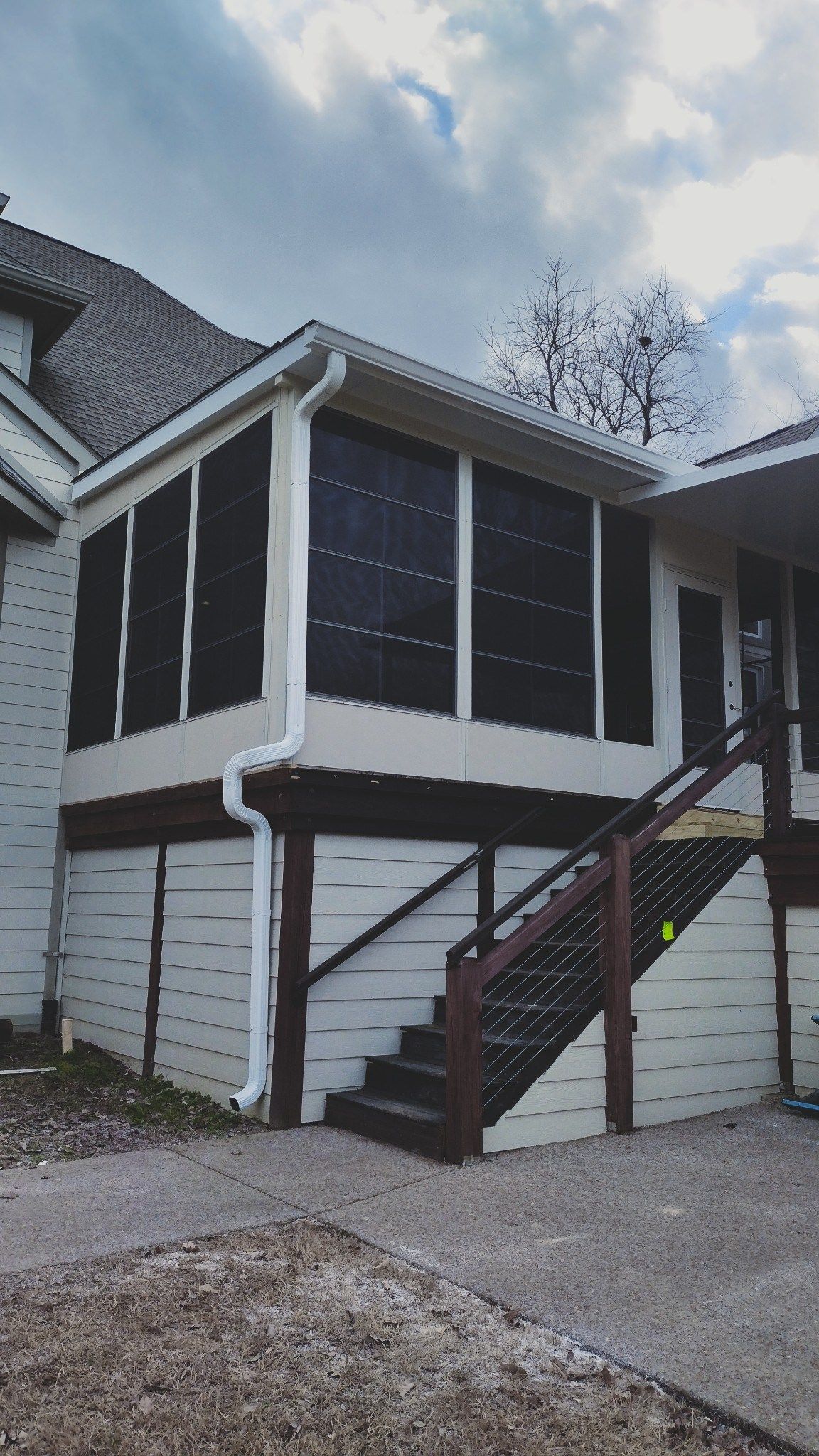 White house exterior with screened porch, dark roof, and stairway to a raised entrance.