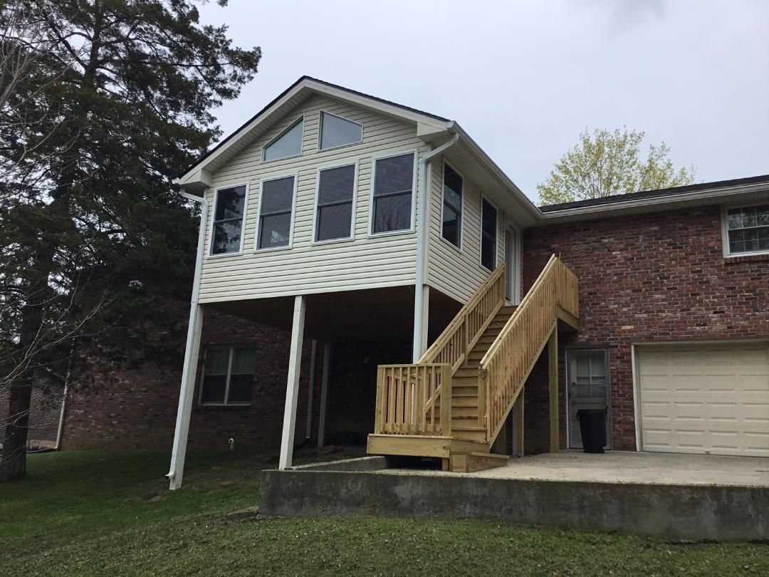 Two-story brick house with a covered porch, exterior staircase, and beige garage door