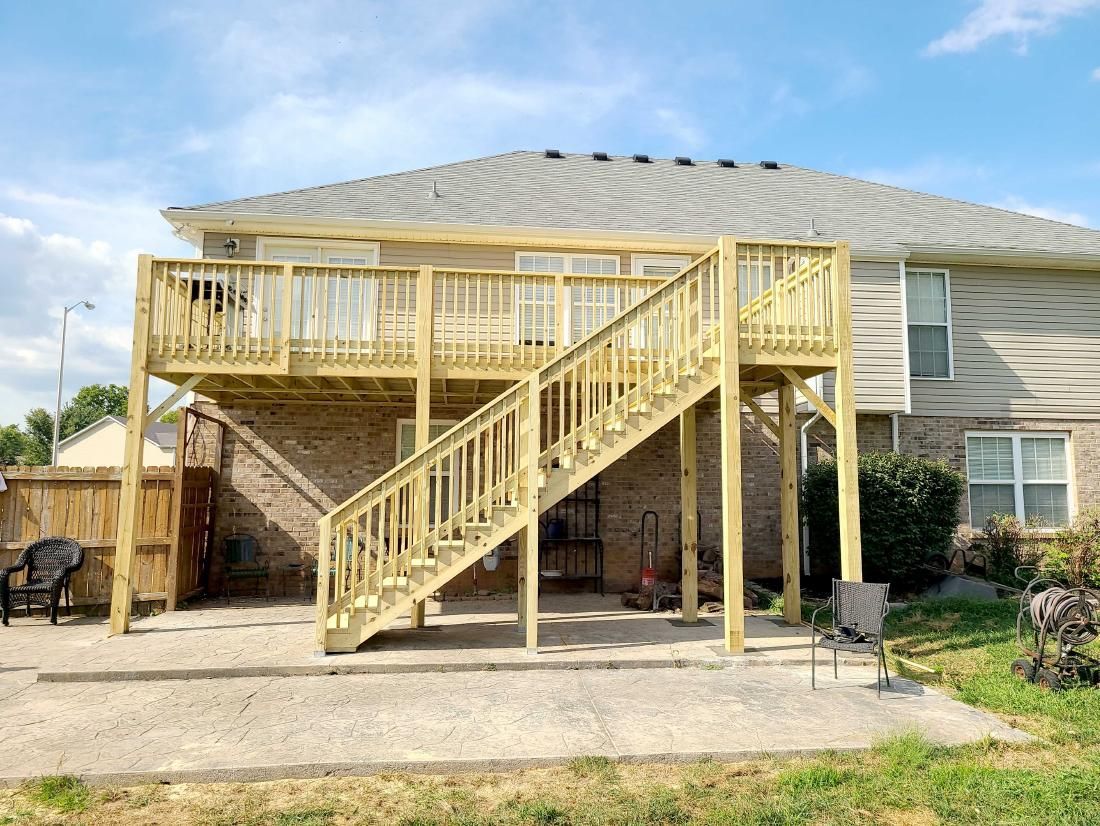 Backyard wooden deck with stairs and railing attached to a house