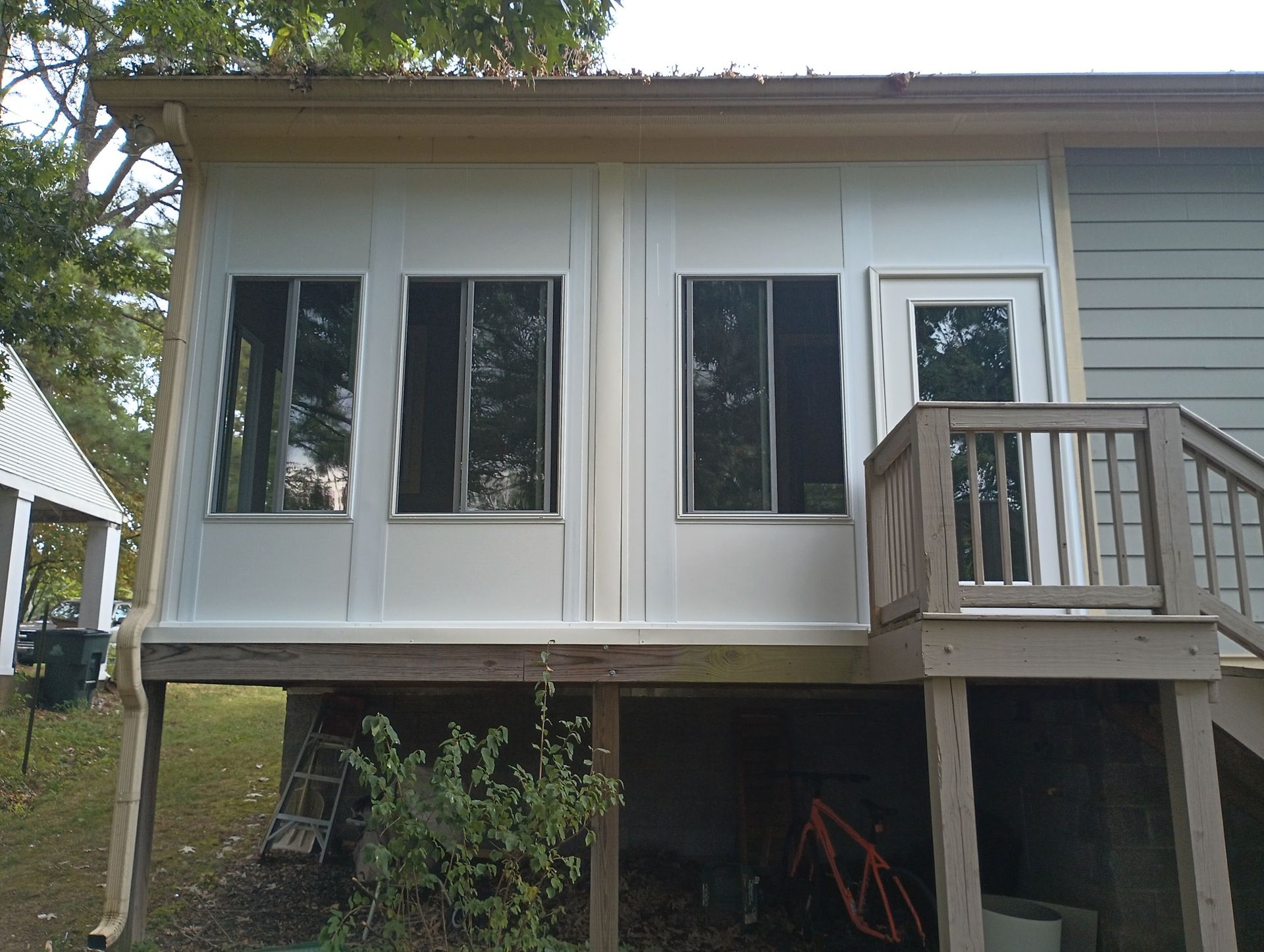 Raised house exterior with large windows, small deck, and stairs underneath