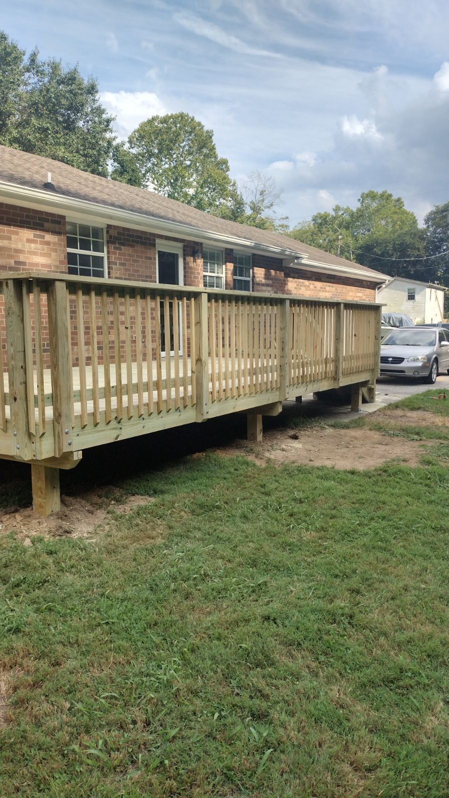Wooden ramp beside a brick building, leading to a raised entrance in a grassy yard.