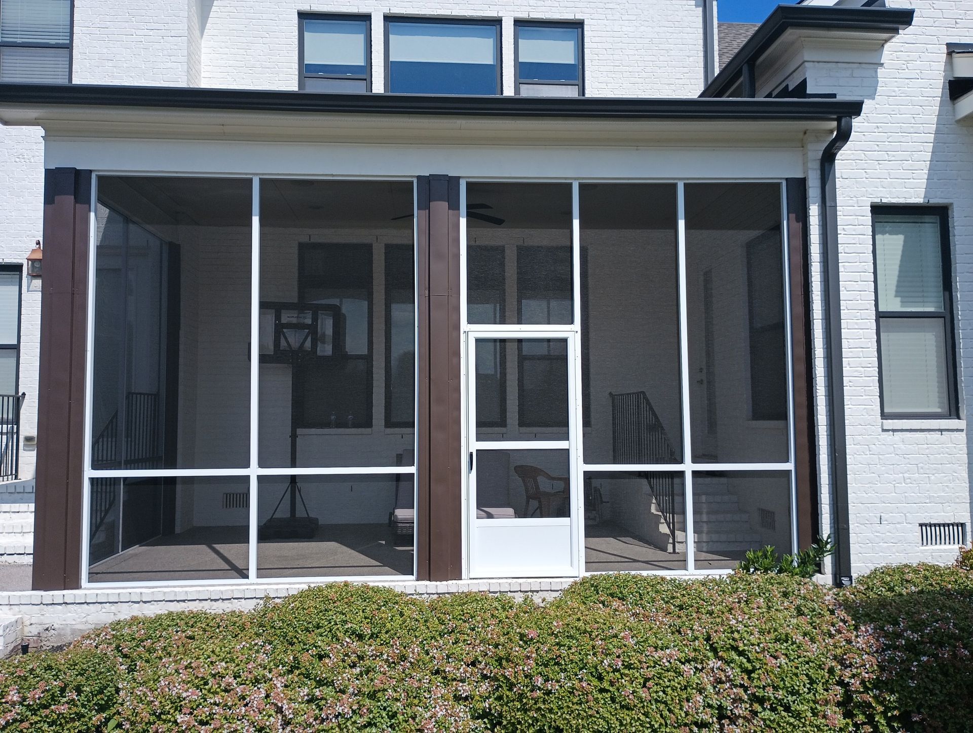 Front porch with screened enclosure and white door on a brick house