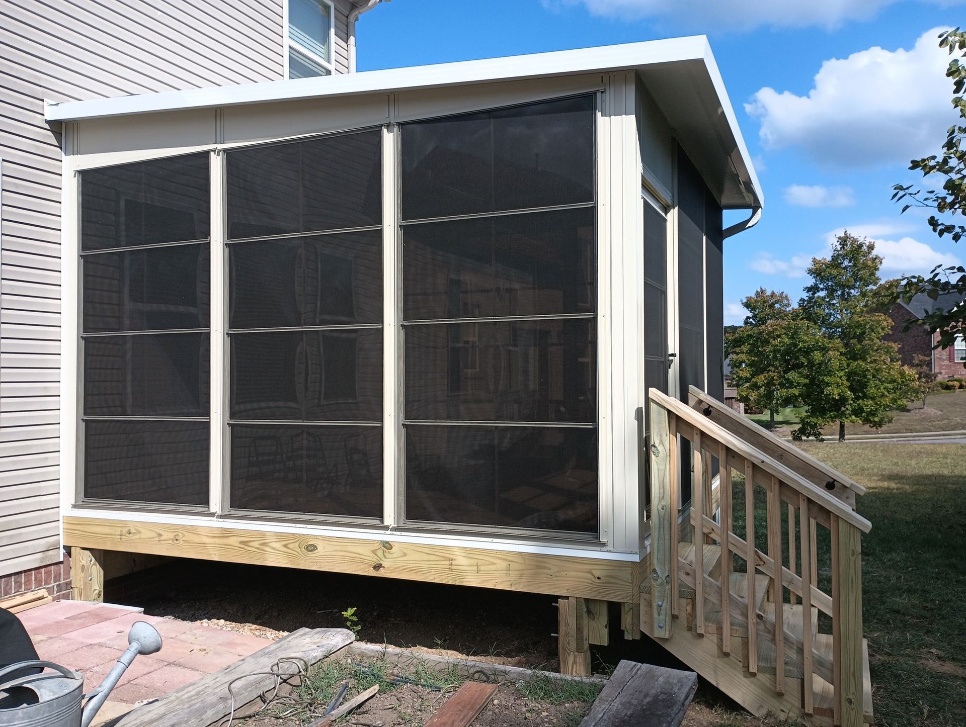 Screened porch enclosure with a wooden ramp beside a house