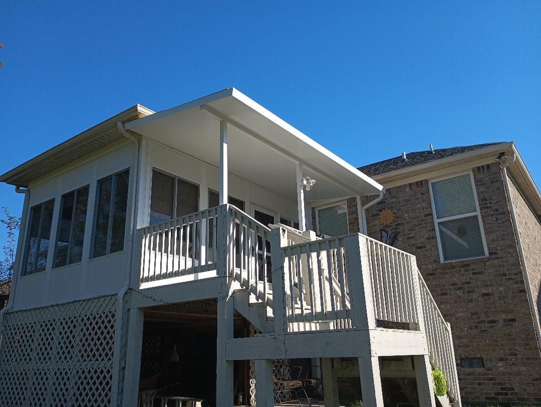 Outdoor patio with wooden chairs, stone fire pit, and a shaded house deck under a white pergola