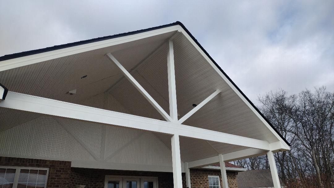 White-roofed building entrance with exposed trusses and columns under a cloudy sky