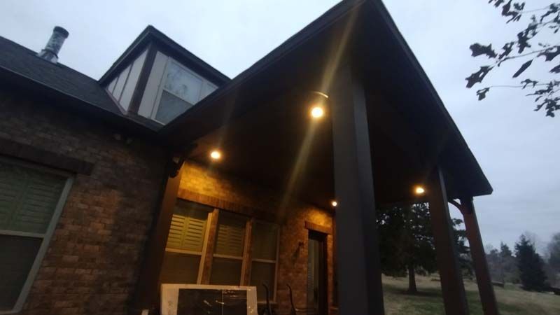 Brick house porch at dusk with warm exterior lights and a steep peaked roof.