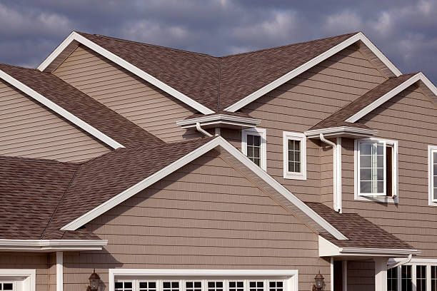 Suburban house with brown shingle roof and beige siding under cloudy sky