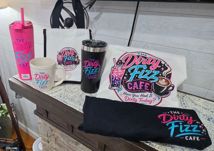 Dairy Fizz Cafe branded cups, tumbler, and ice cream on a table at a stand.