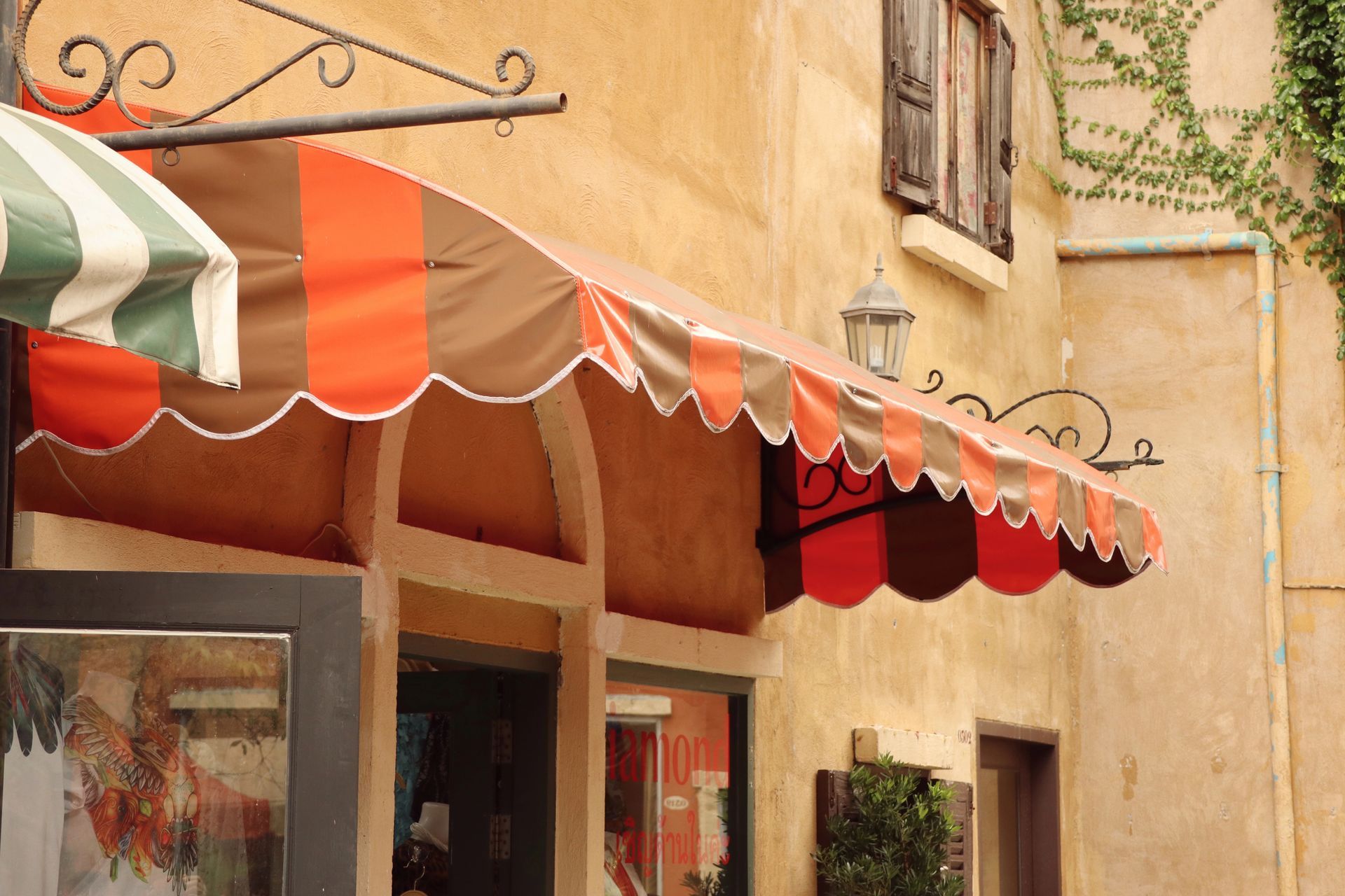 Tenda a strisce arancioni e marroni sopra l'ingresso di un negozio con finiture smerlate.