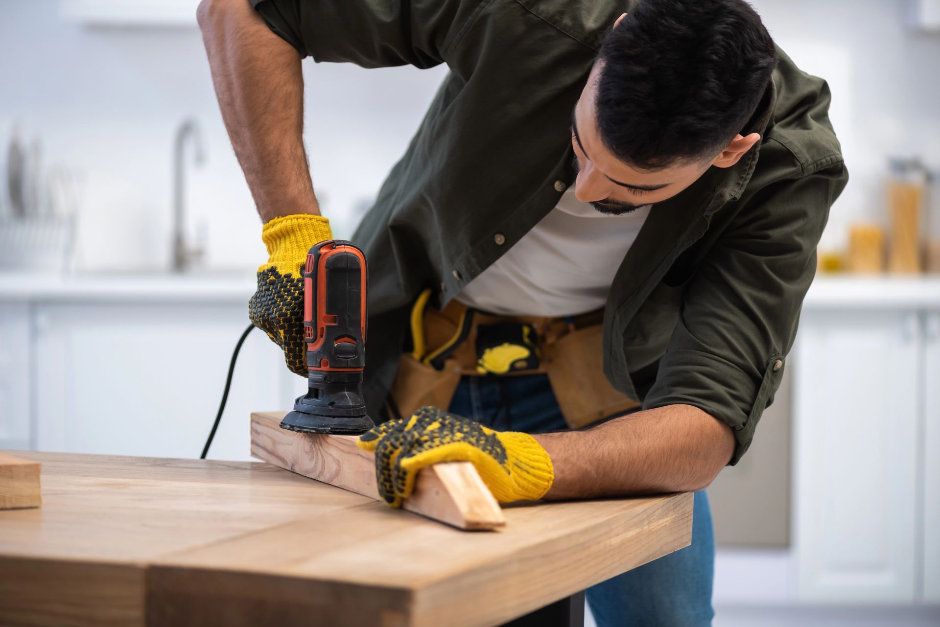 Persona che utilizza una levigatrice elettrica sul legno su un banco da lavoro