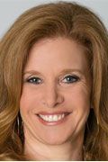 Woman with auburn hair, smiling; wearing earrings.
