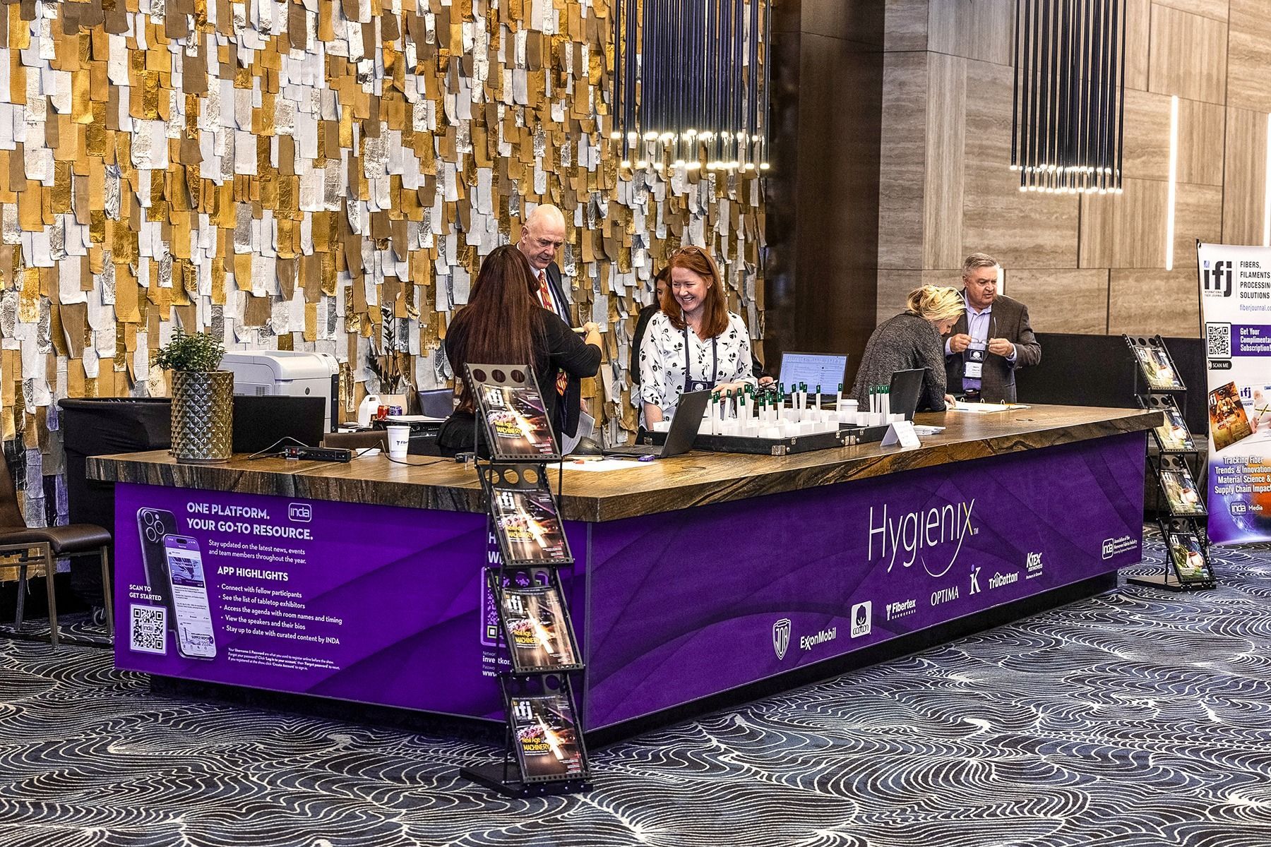 Registration desk with purple signage and three people assisting attendees.
