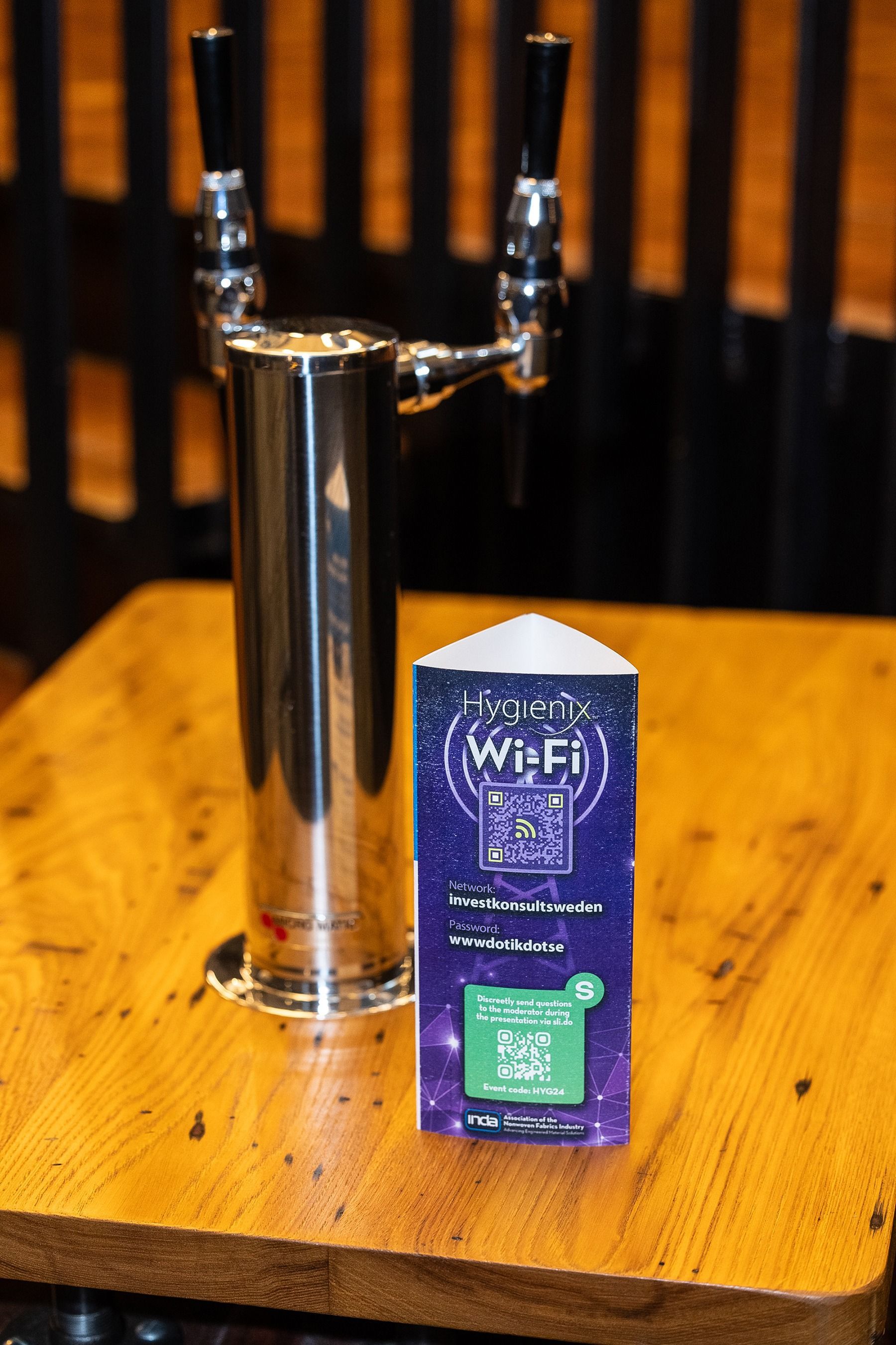 A beer tap and a sign with Wi-Fi information on a wooden table.