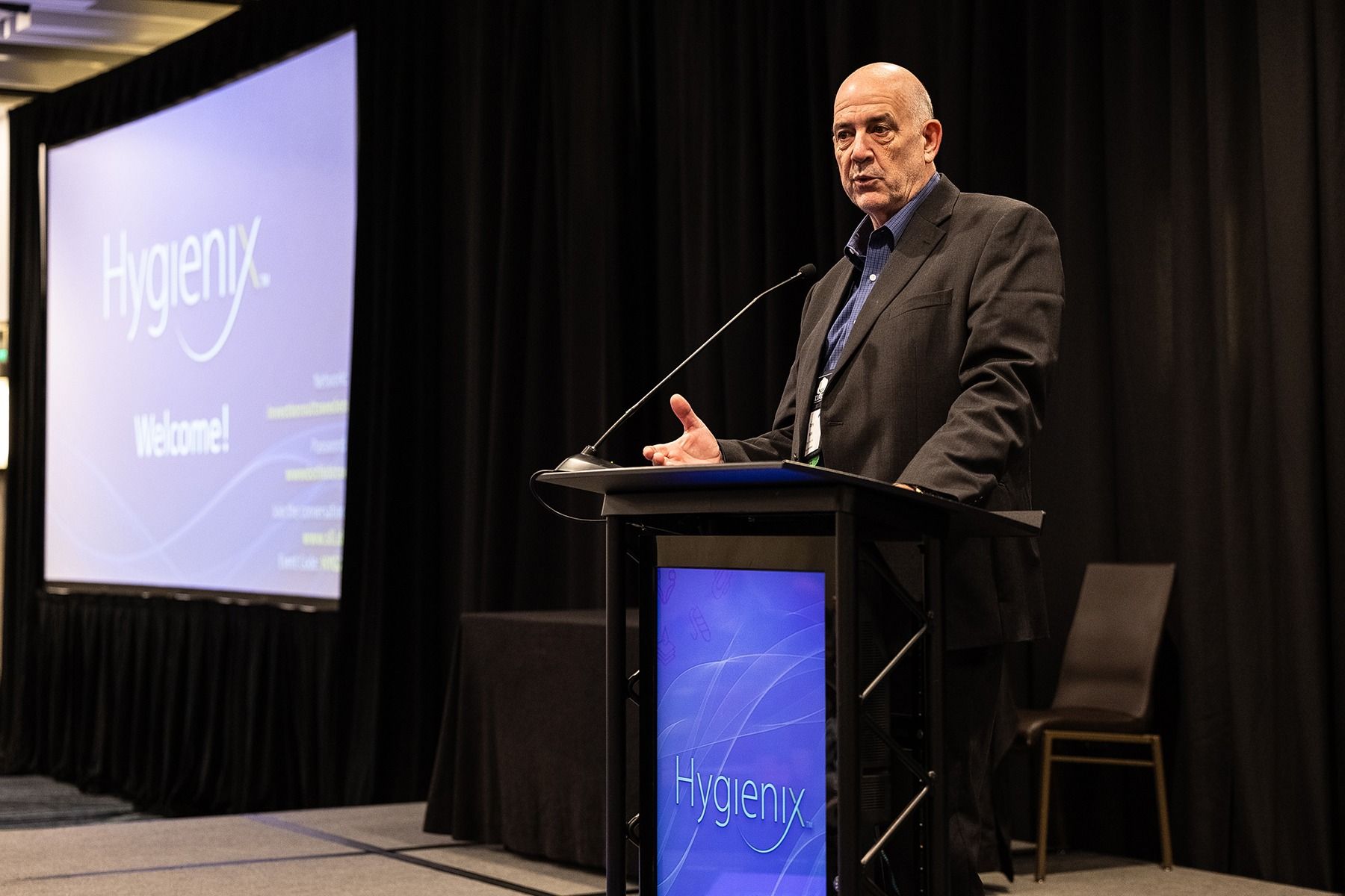 Man speaking at a podium in front of a screen at the Hygenix conference.