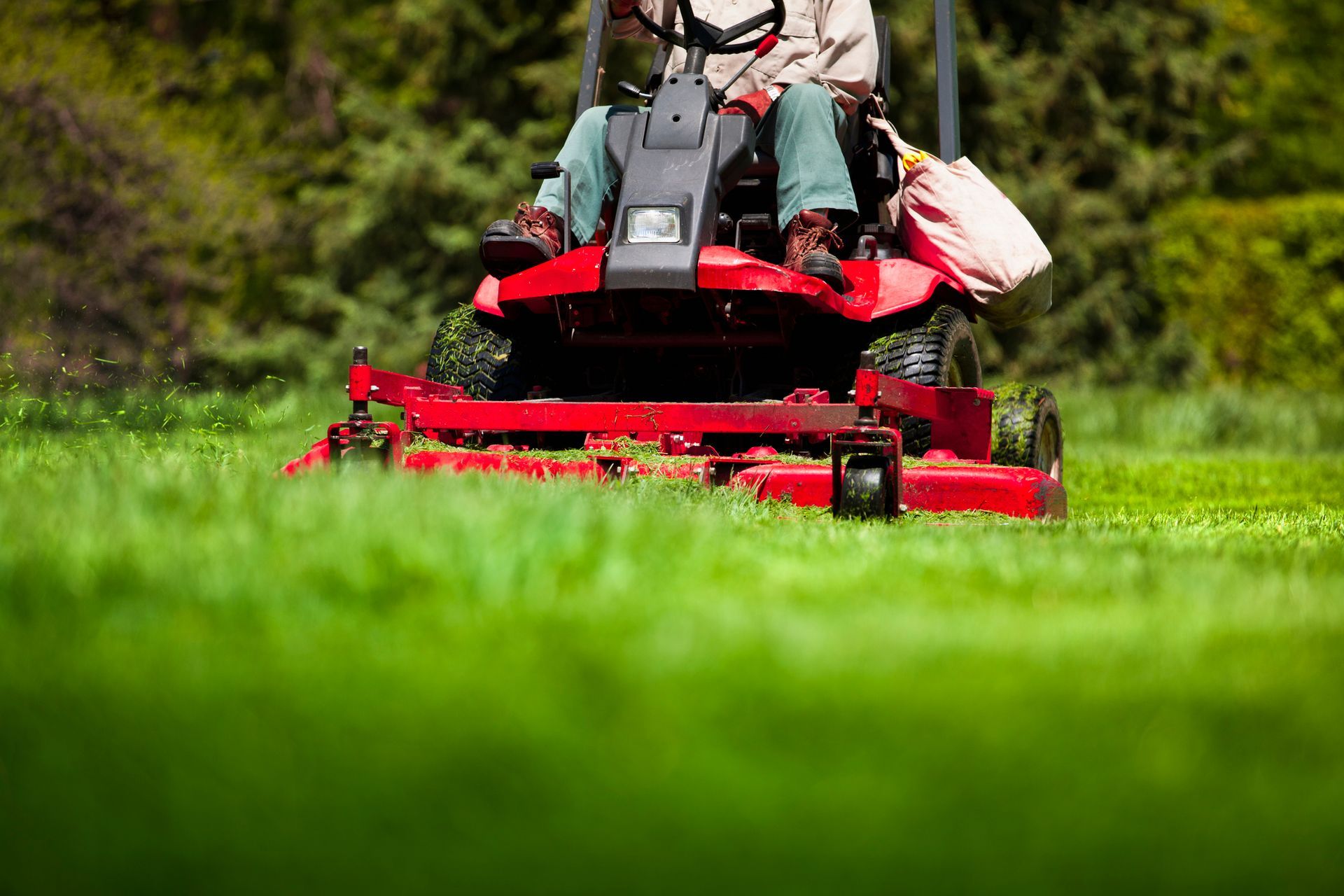A Man Is Riding a Red Lawn Mower on A Lush Green Lawn | Clinton, OH | Flexlawn & Landscape, LTD