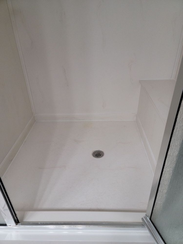 White shower stall with a central drain and glass doors on both sides.