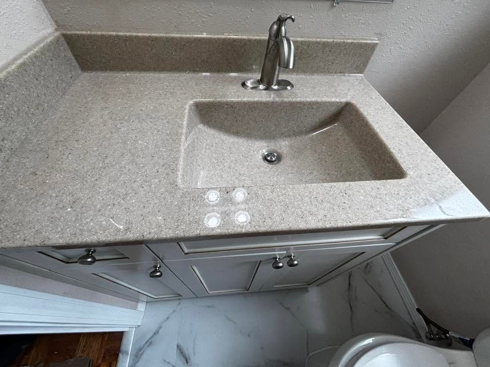 Granite bathroom vanity with single sink, chrome faucet, and white cabinet doors underneath