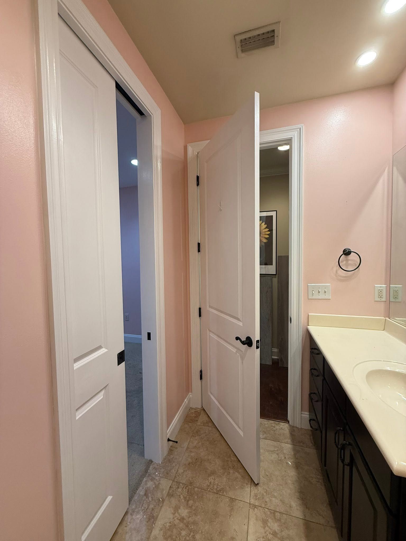 Bathroom with pink walls, white doors, tiled floor, and a vanity sink on the right.