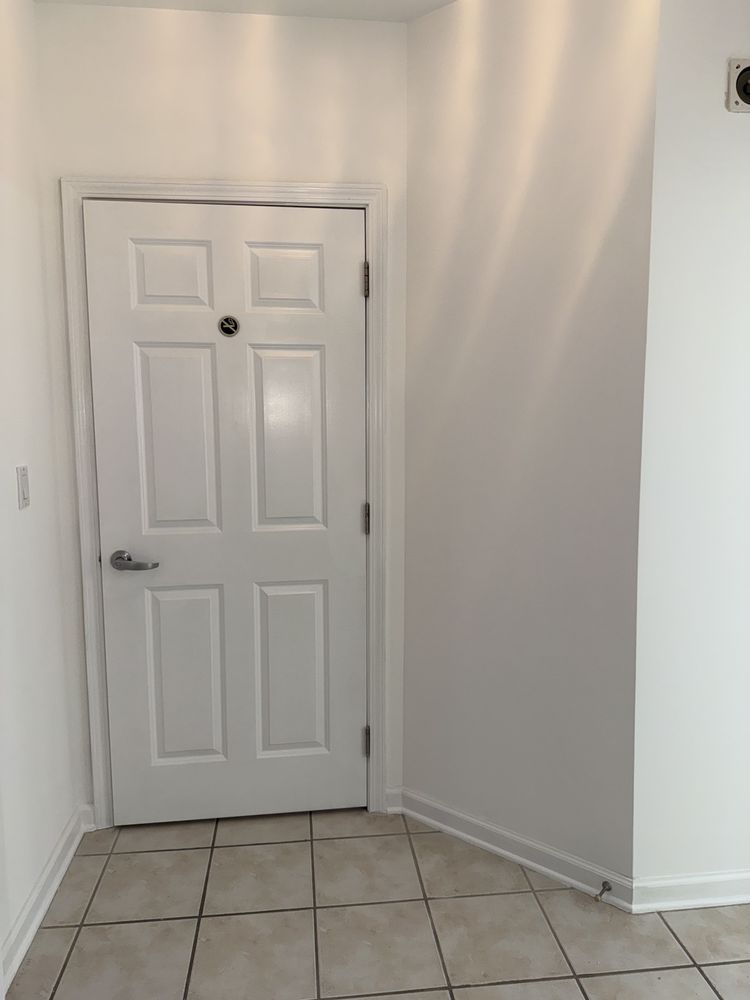 White paneled door in a small tiled hallway with white walls and baseboards.
