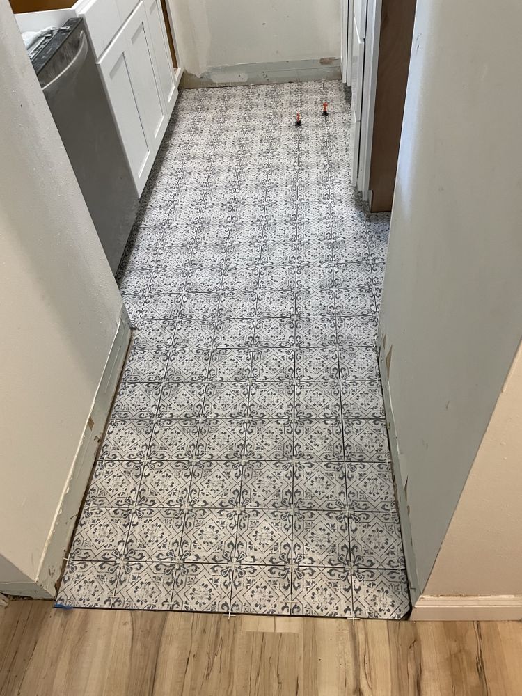 Narrow kitchen hallway with patterned floor runner and white walls, leading to a doorway.