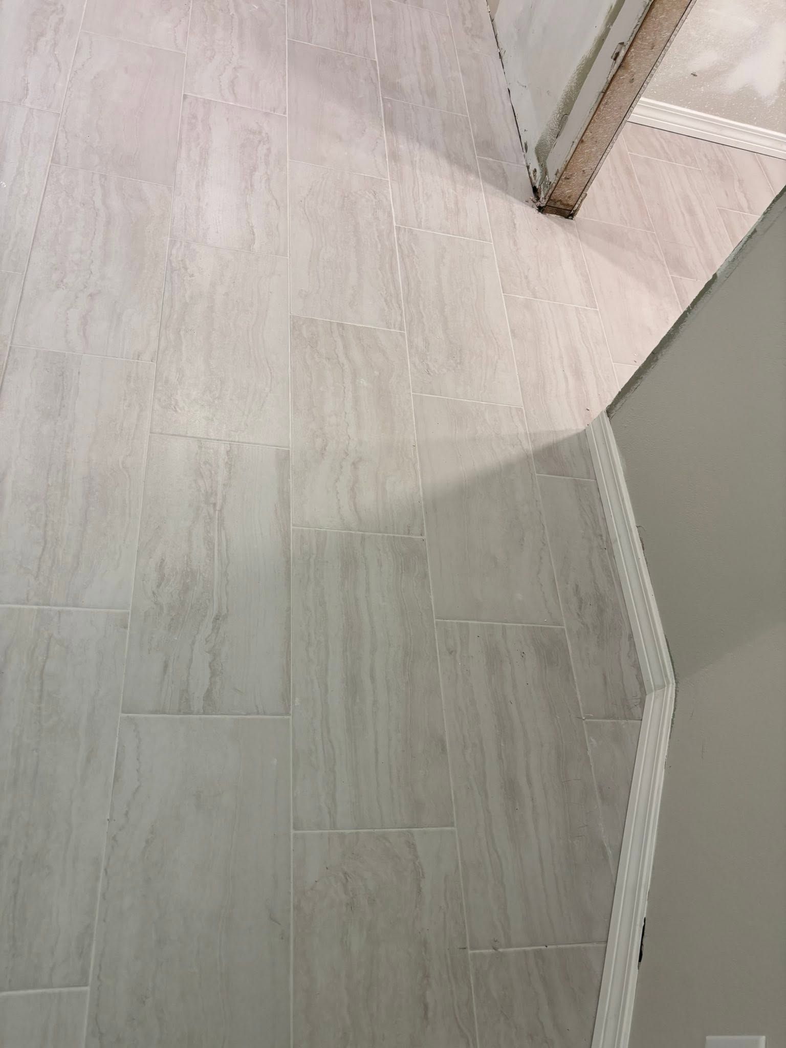 White-tiled floor and curved white wall corner in a bright indoor hallway.