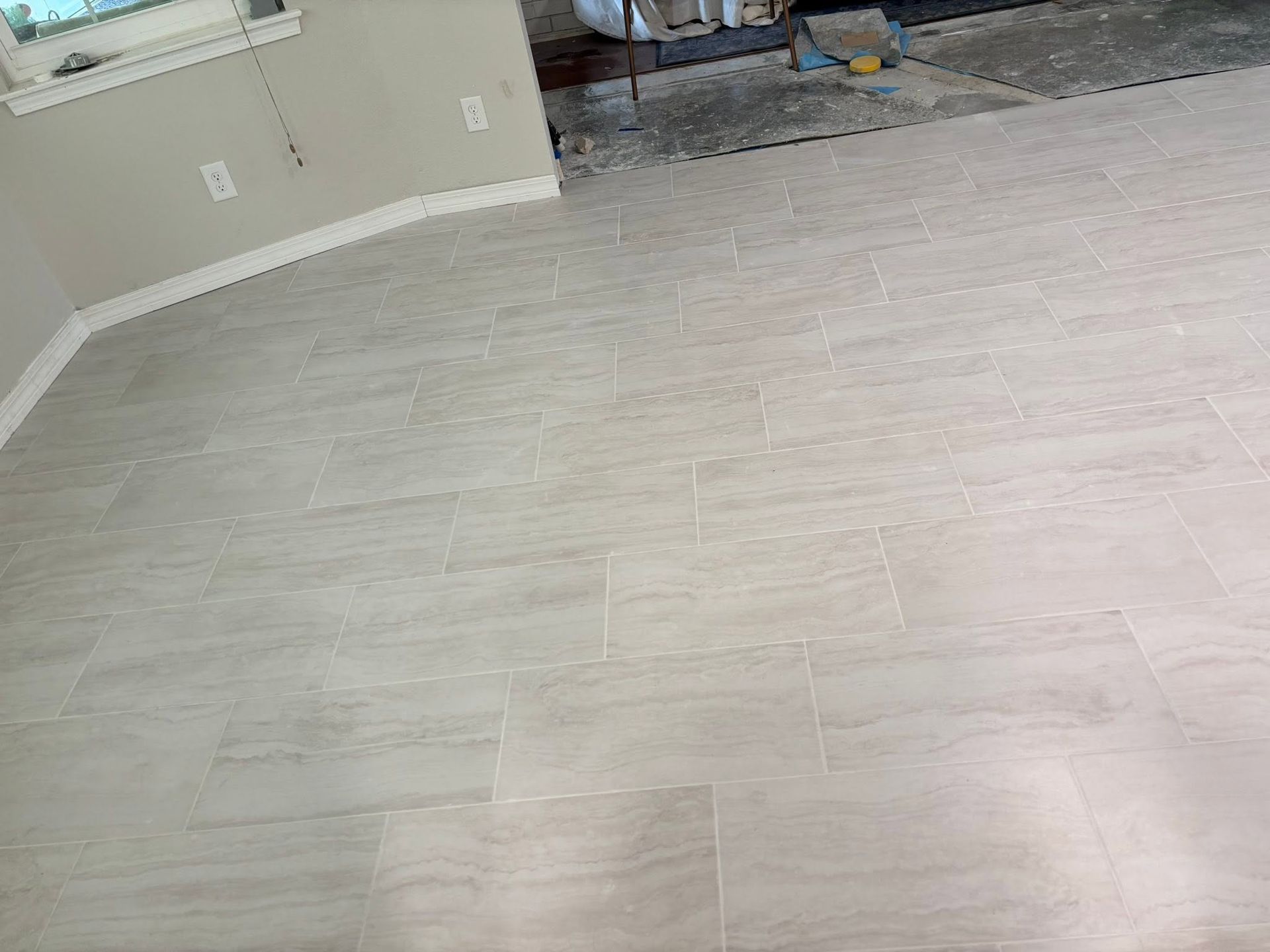 Empty light gray tiled room with beige walls and a doorway to another room
