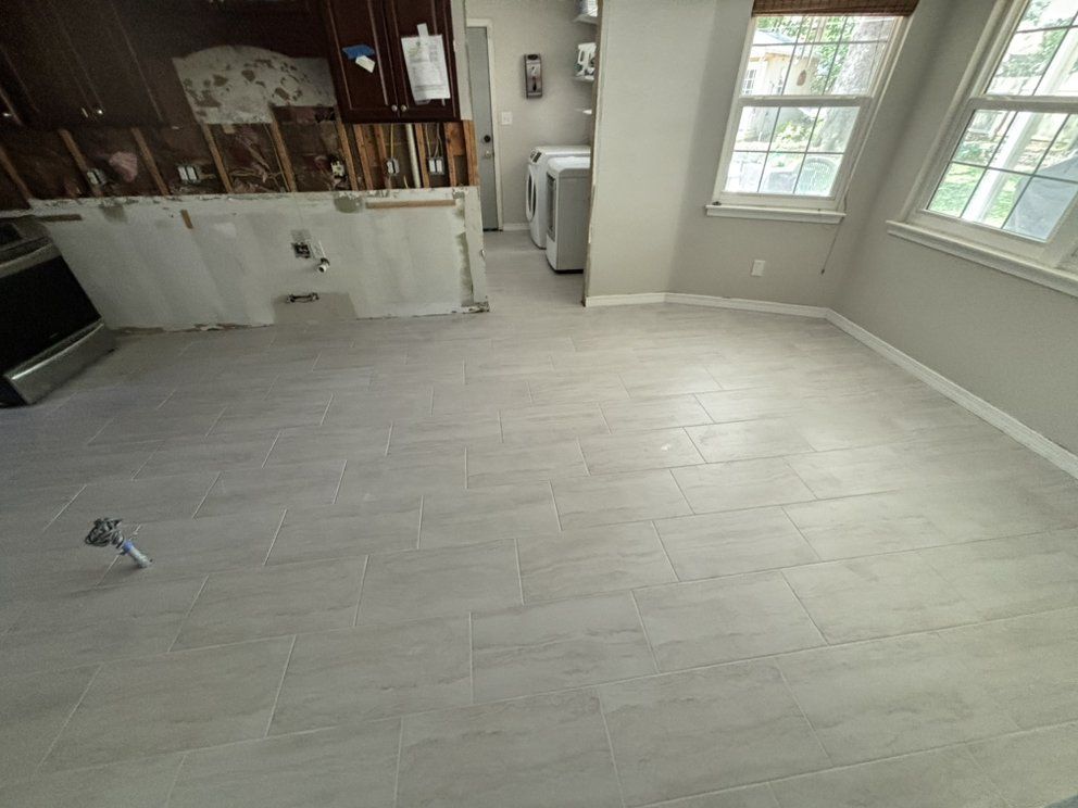 Empty kitchen with light gray wood-look flooring, white walls, and windows letting in daylight