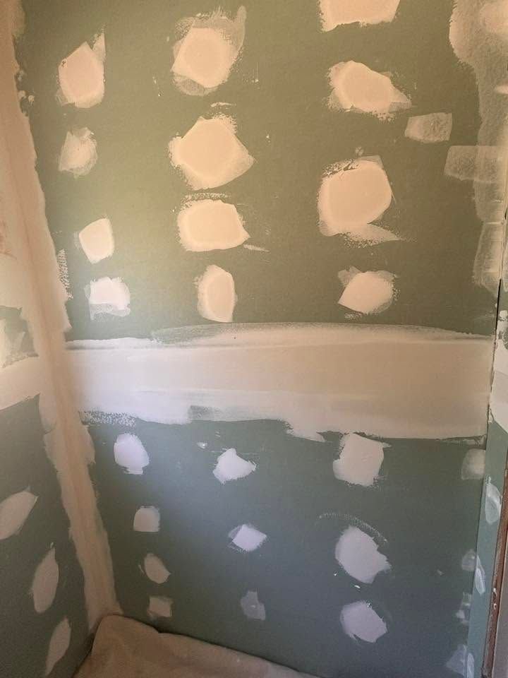 Drywall corner with green board, white joint compound patches, and a horizontal taped seam.