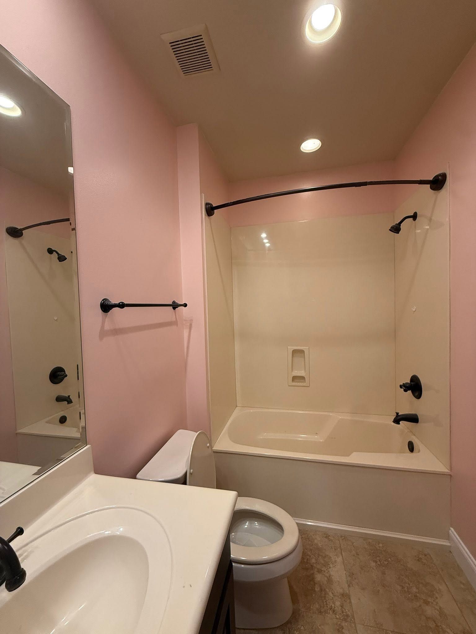 Small pink bathroom with a sink, toilet, and bathtub/shower alcove.