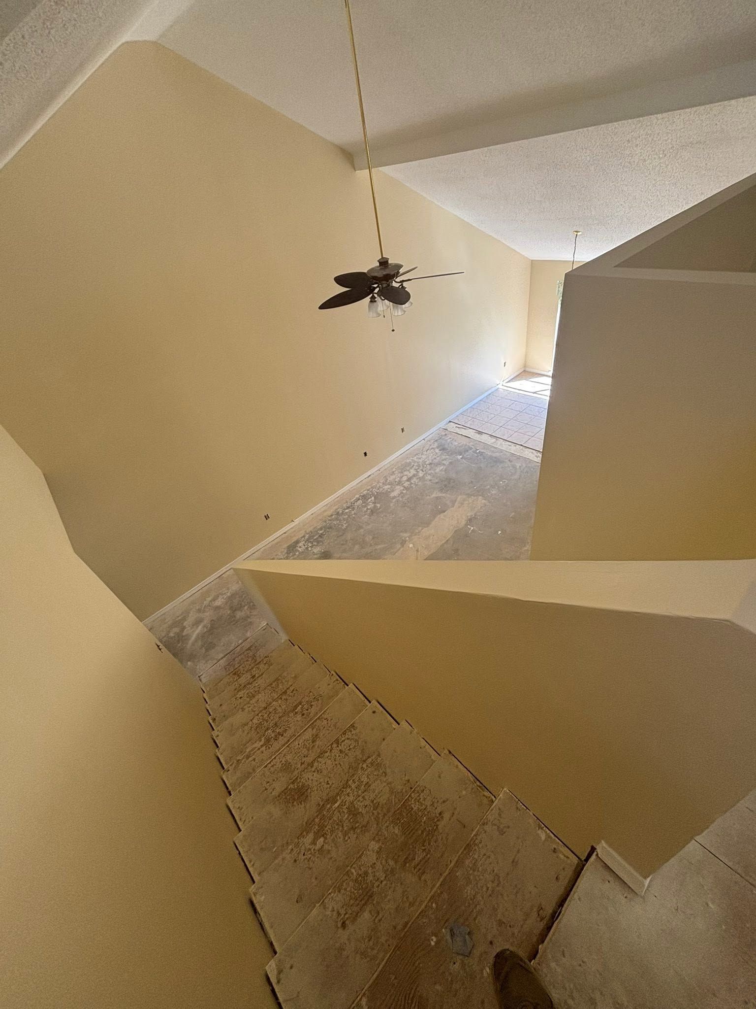 Indoor hallway with beige walls and tiled floor, viewed from above toward a bright opening.