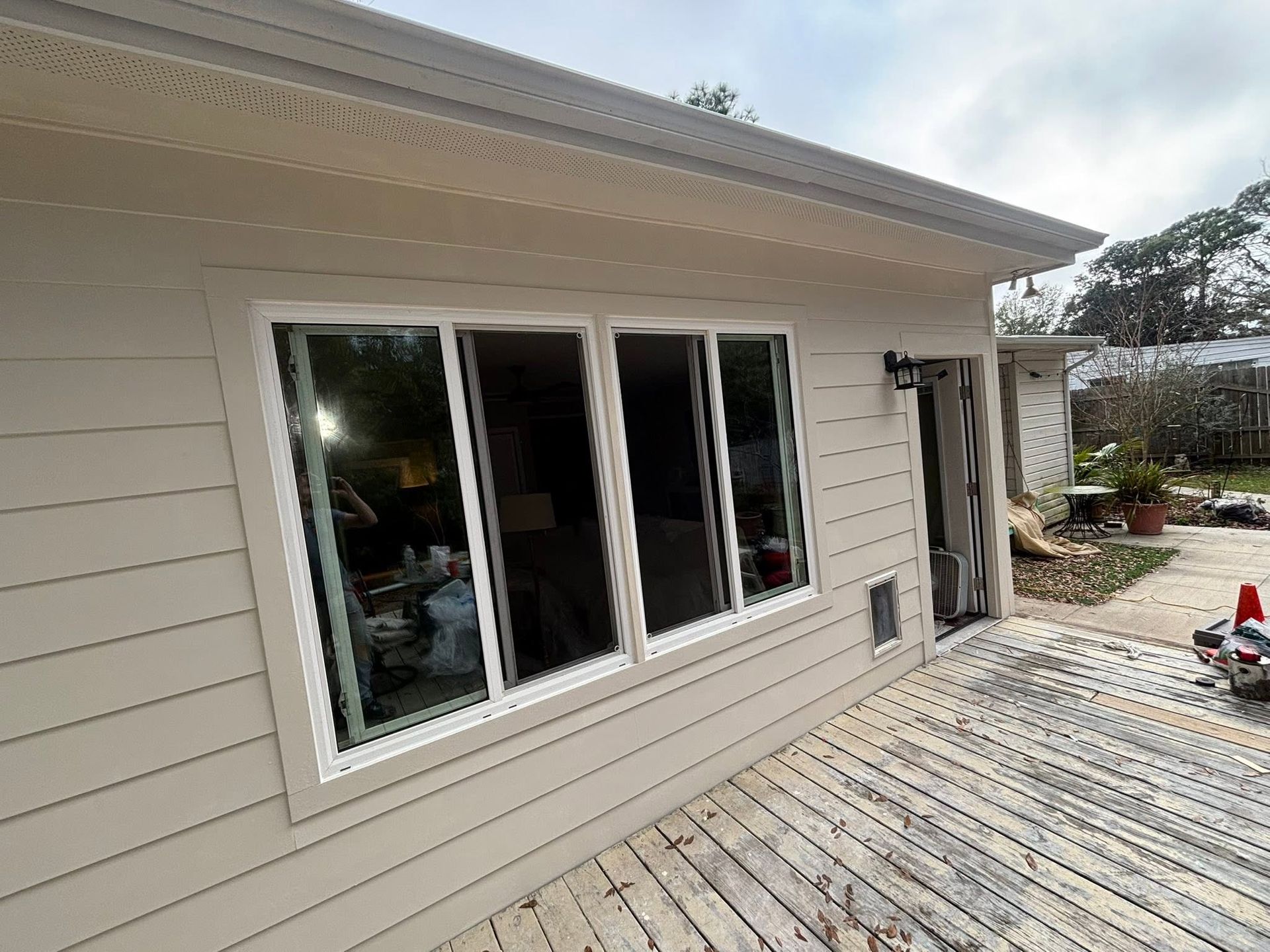 Side of beige house with sliding glass doors and a weathered wooden deck under construction