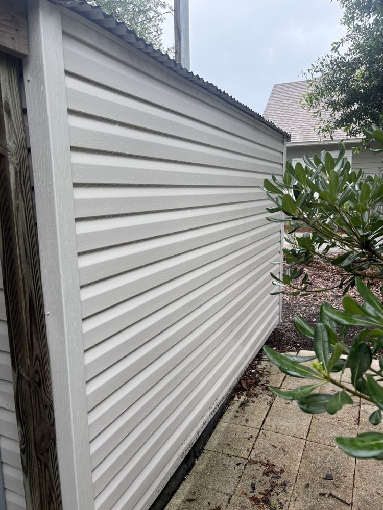 White vinyl-sided building exterior beside a paved walkway and leafy plants