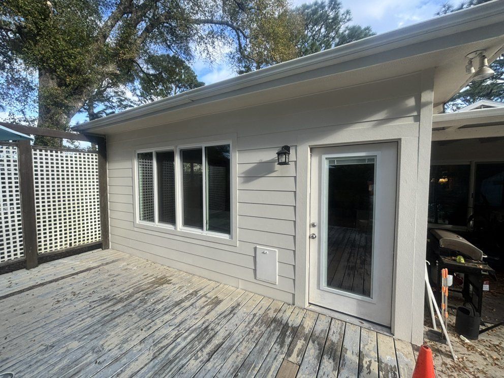 Patio outside a gray house with sliding glass door, windows, and white lattice fence