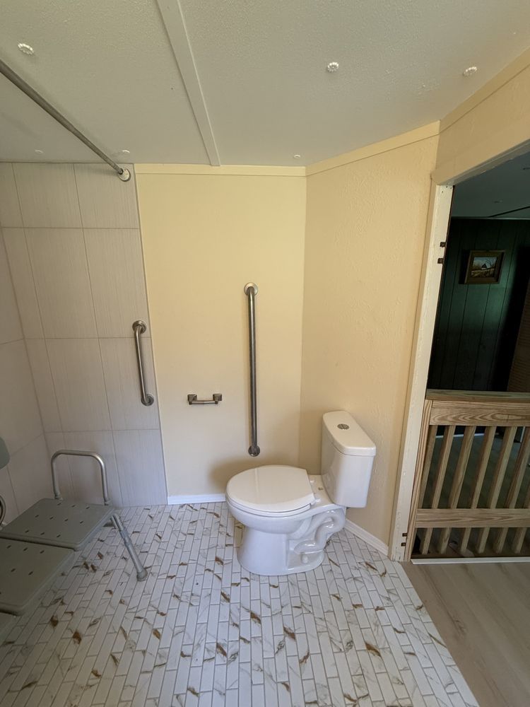 Small bathroom with a toilet, shower area, and tiled floor in beige and white.