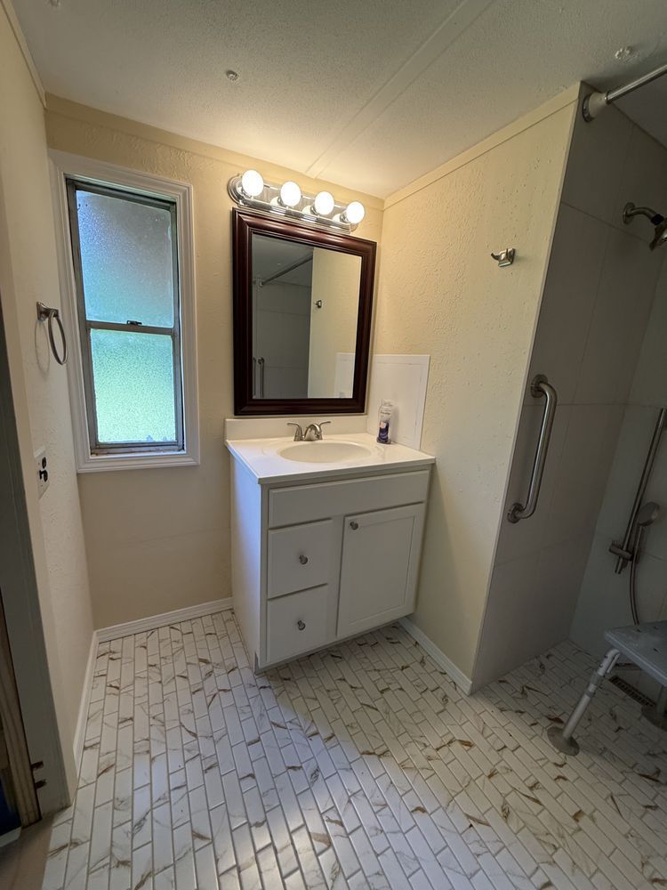 Small bathroom with white vanity, mirror lights, tiled floor, and shower curtain.