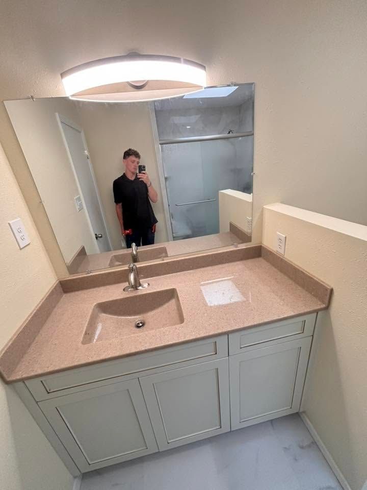 Bathroom vanity with sink and large mirror, showing a person reflected in the mirror.