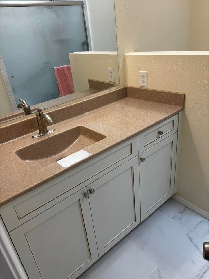 Bathroom vanity with beige countertop, white cabinets, sink, and mirror.