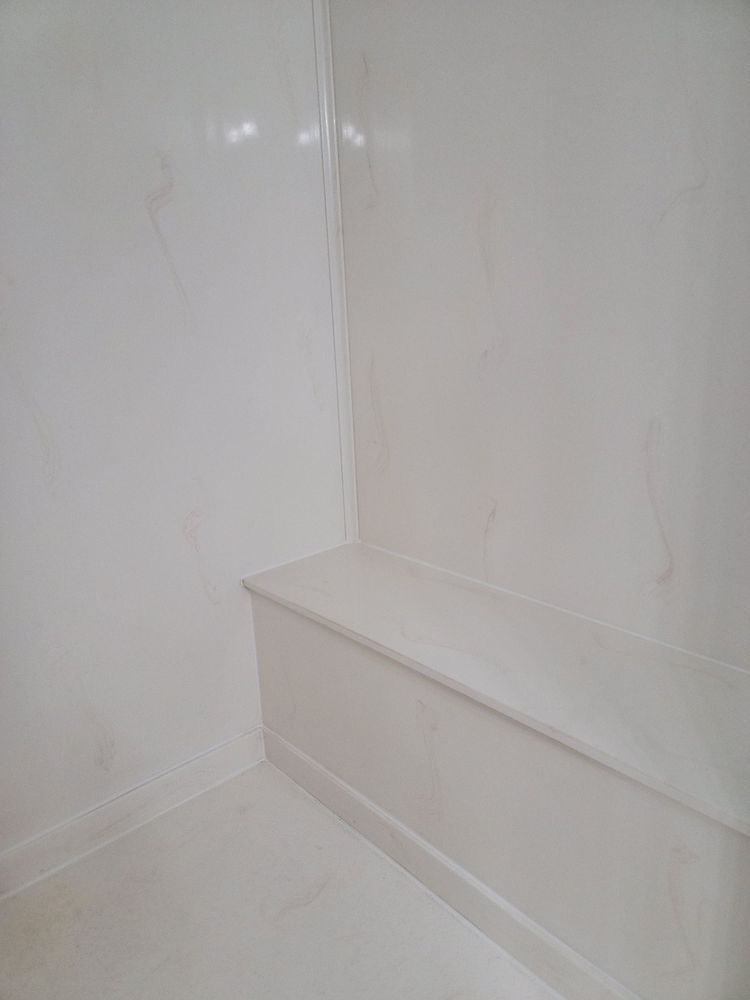 Empty white corner with a built-in bench and glossy wall paneling
