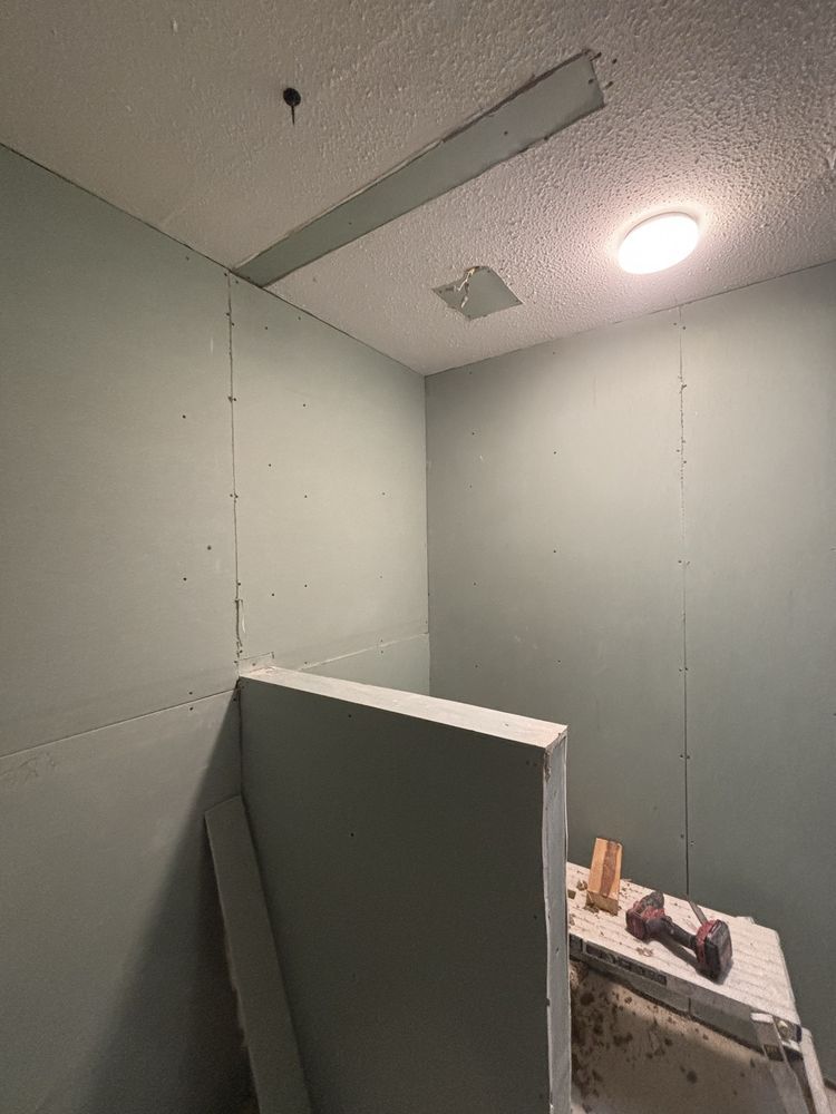 Damaged ceiling panel in a small room, with a broken partition leaning in the foreground.