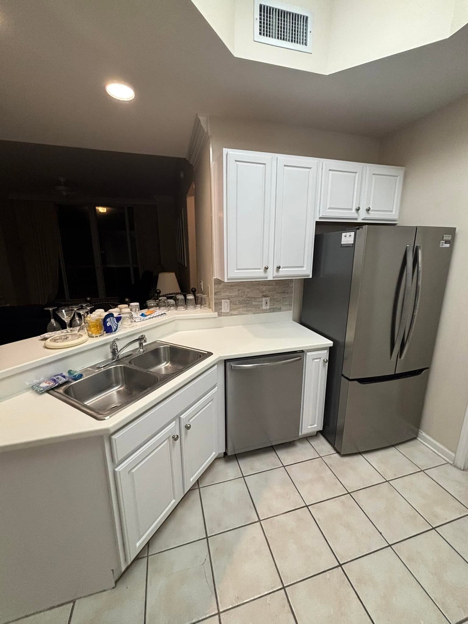 Modern kitchen with white cabinets, stainless steel appliances, tiled floor, and granite countertop
