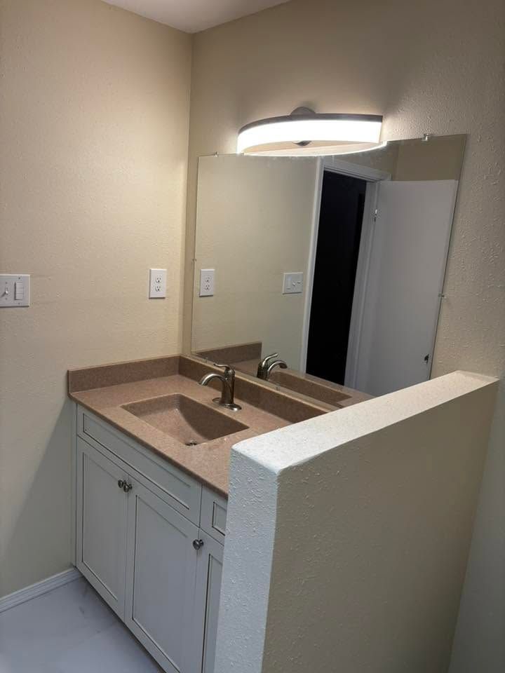 Bathroom vanity with sink, mirror, and light fixture in a beige room