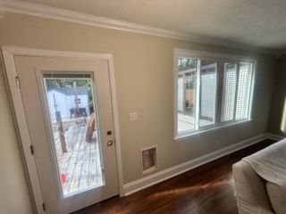 Living room with beige walls, a glass patio door, a window, and a beige sofa.