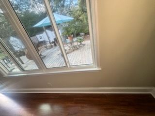 Empty room with dark wood floor and a large window overlooking a patio with an umbrella